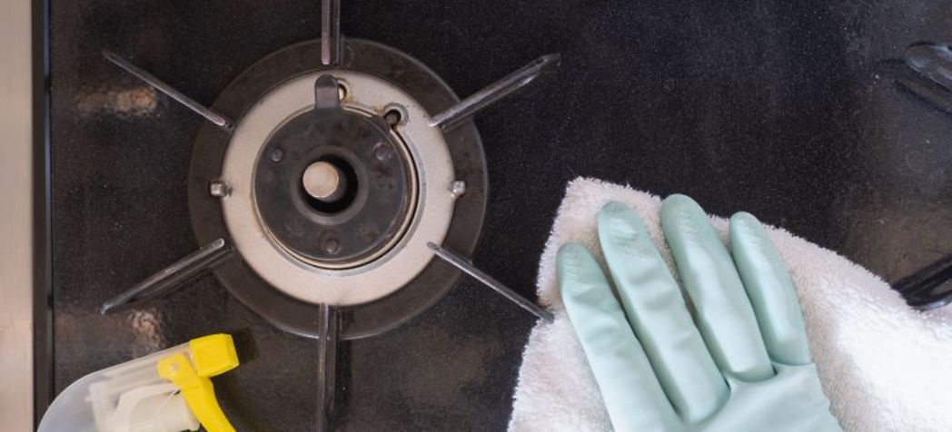 gloved hand washing down a burner - Jade Range Burner Cleaning Instructions