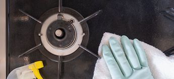 gloved hand washing down a burner - Jade Range Burner Cleaning Instructions