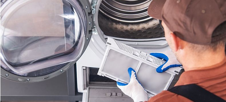 Service Technician cleaning and maintaining commercial dryer - Commercial gas dryer maintenance and cleaning