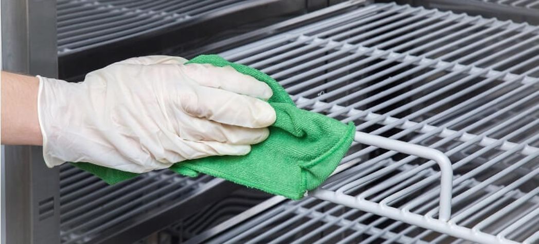 Employee cleaning an oven rack with a washcloth - Revent oven cleaning 