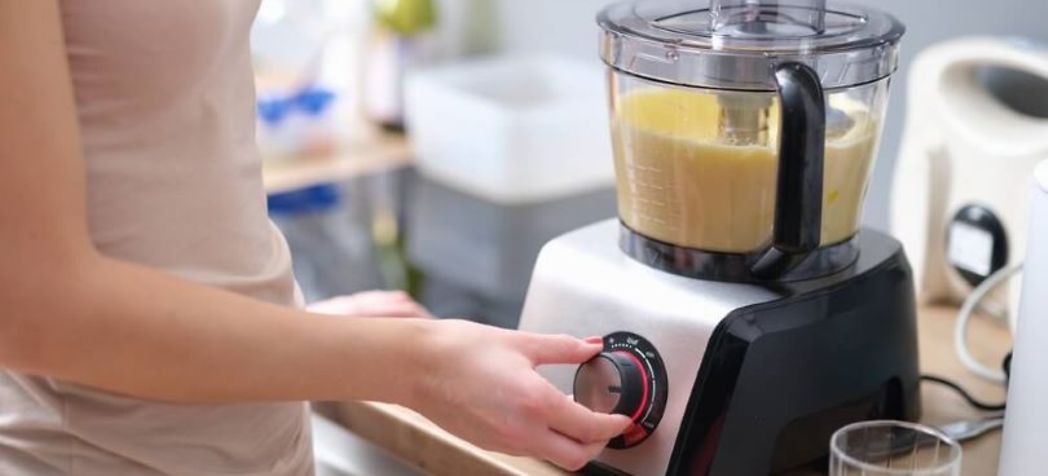 Woman pressing buttons on a food processor - How to Use a Food Processor