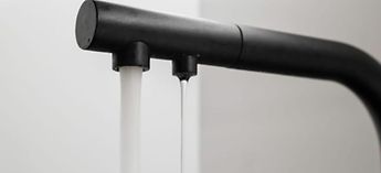 Black faucet with running water - How Everpure PFAS water filtration fights contamination