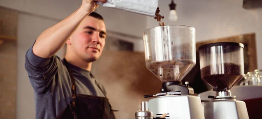 Man filling a coffee grinder with beans - Eureka grinder cleaning