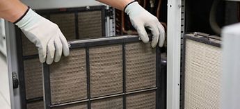 man with gloves removing hvac filter - merv vs hepa filter