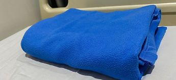 folded blue blanket on hospital bed - common problems with blanket warmers and warming cabinets