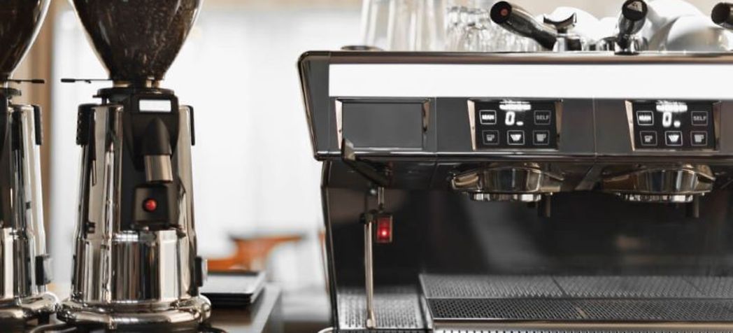 Commercial espresso machine next to bean grinders - nespresso vertuo descaling guide
