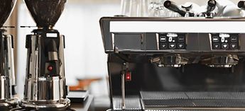 Commercial espresso machine next to bean grinders - nespresso vertuo descaling guide