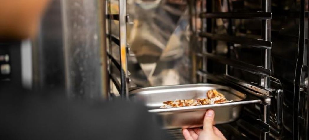 chef putting a dish in a combi oven - Henny Penny Combi Oven Preventative Maintenance