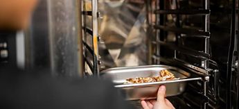 chef putting a dish in a combi oven - Henny Penny Combi Oven Preventative Maintenance